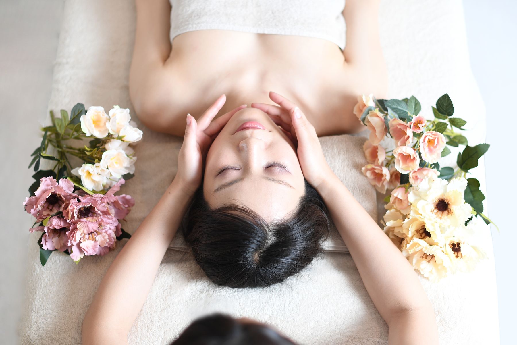 花に囲まれてフェイシャルケアを受ける女性